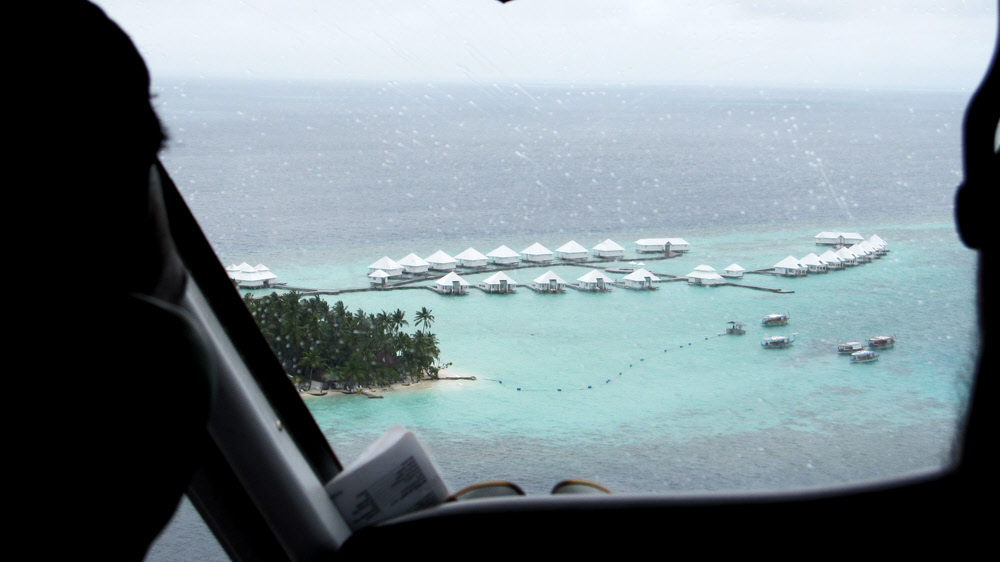 Coming in to land at Athuruga in a rainshower - view over the pilot's shoulder showing the new Water Village to the west of the island.  (108k)